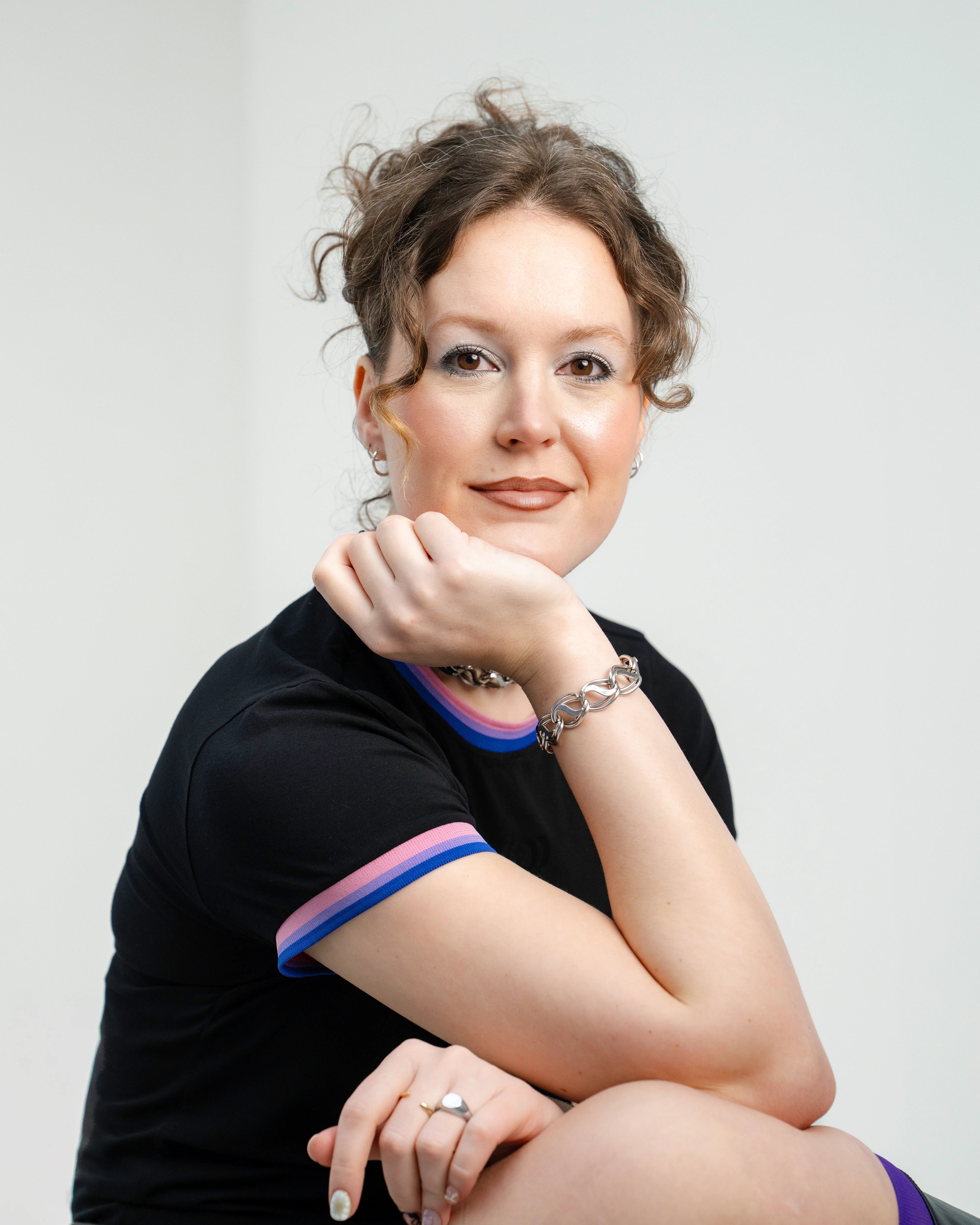 Detailshot of model wearing a black Biweekly Babytee with bi pride flag trim on the collar and sleeves, side view against a white background