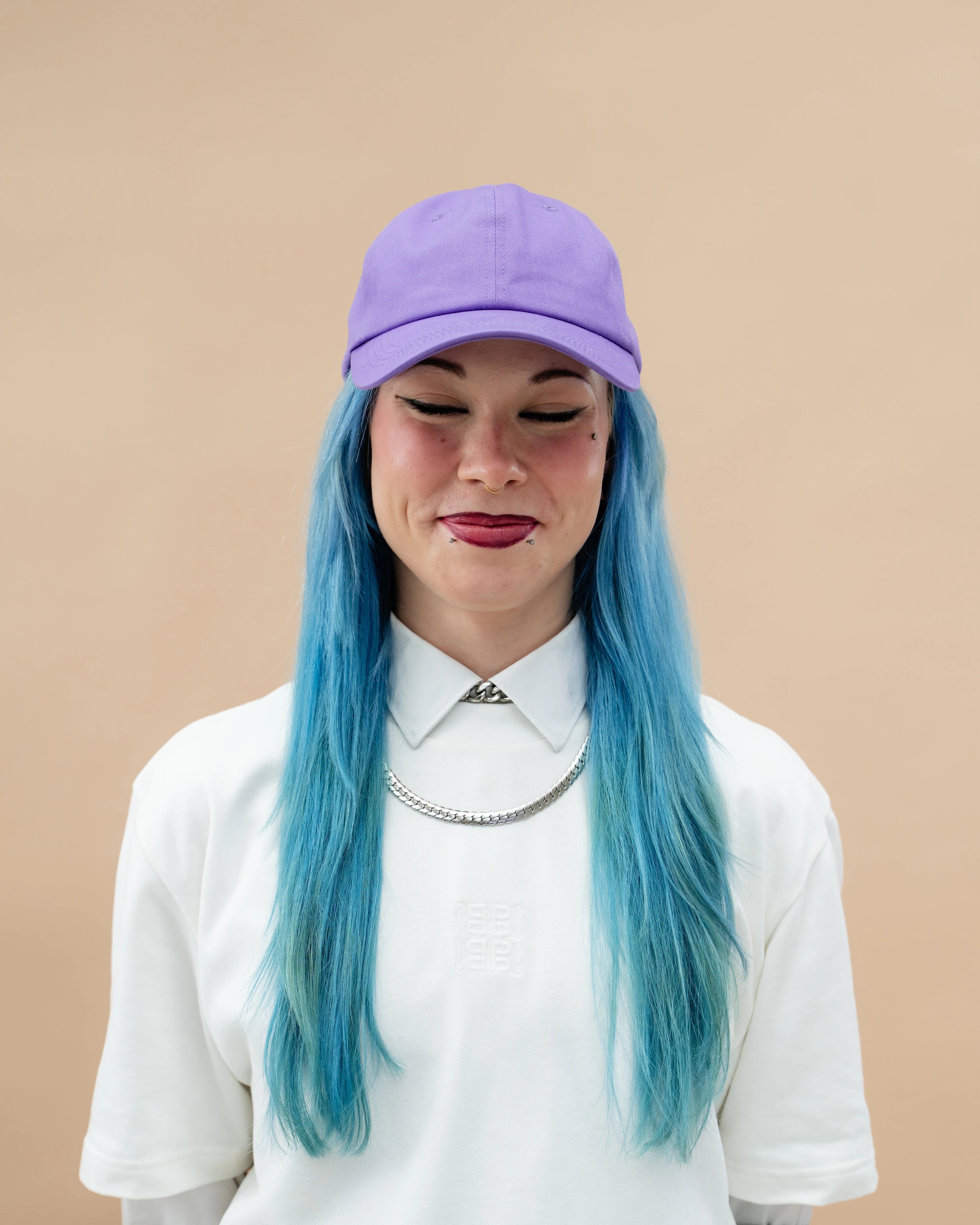 Model wearing a lilac Biweekly cap, front view against a beige background