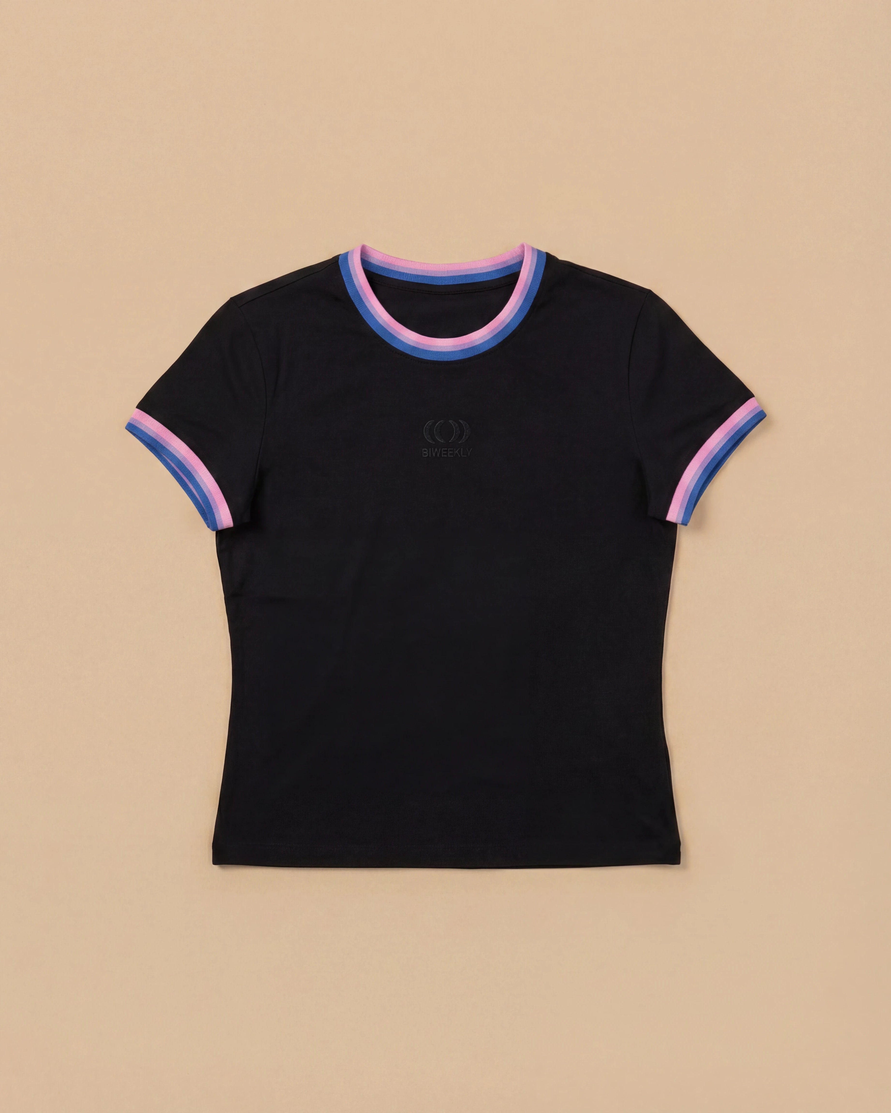 Black Biweekly babytee with bi pride flag trim on the collar and sleeves and black logo in the front, laying flat against a beige background
