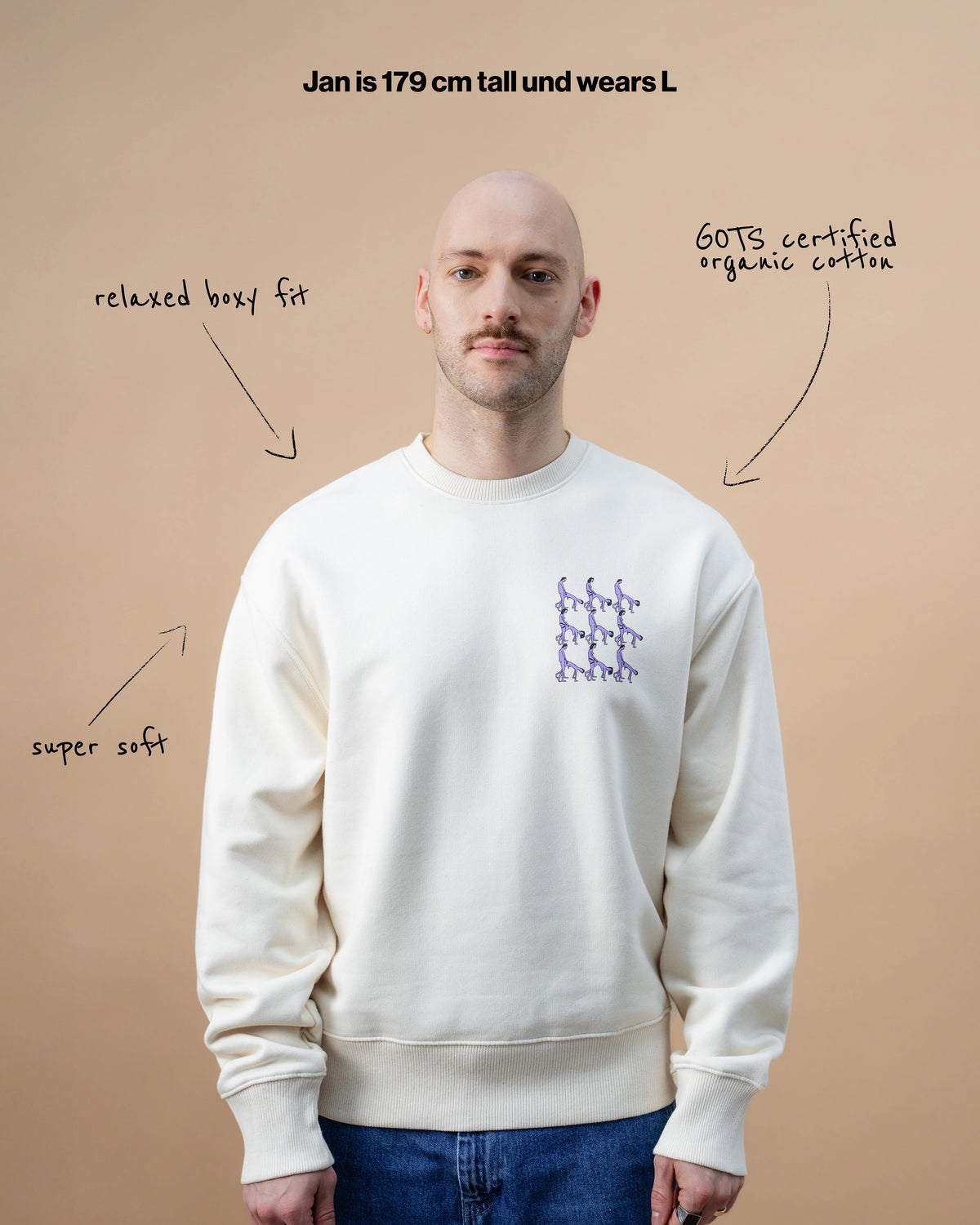 Model wearing a light beige Biweekly crewneck with graphic print of stylized figures in playful poses on the chest, front view against a beige background. Text with arrows that say relaxed boxy fit, super soft, GOTS certified organic cotton and "Jan is 179 cm tall and wears L"