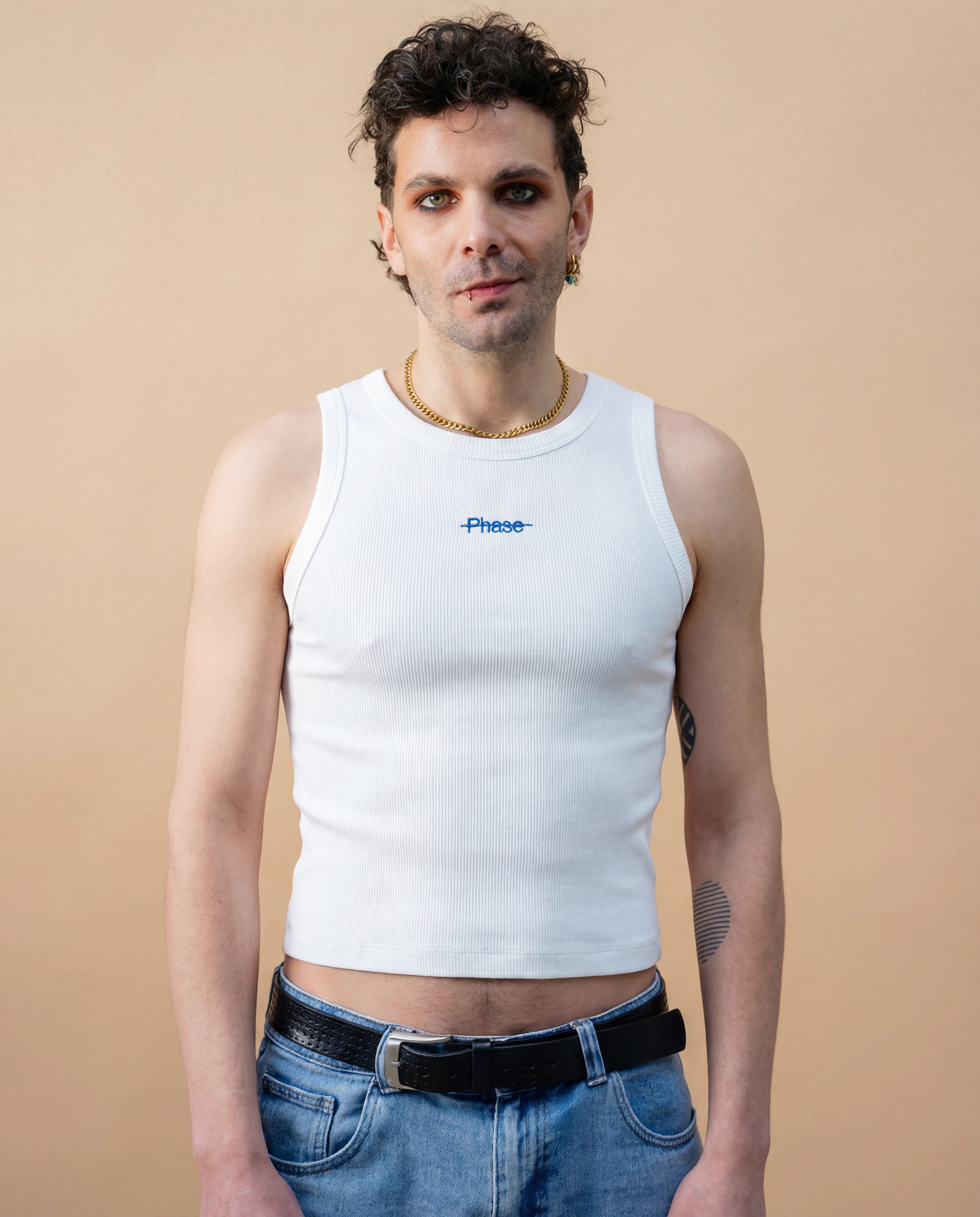 Model wearing a white Biweekly tank top with blue ‘Phase’ text that is crossed out, front view against a beige background
