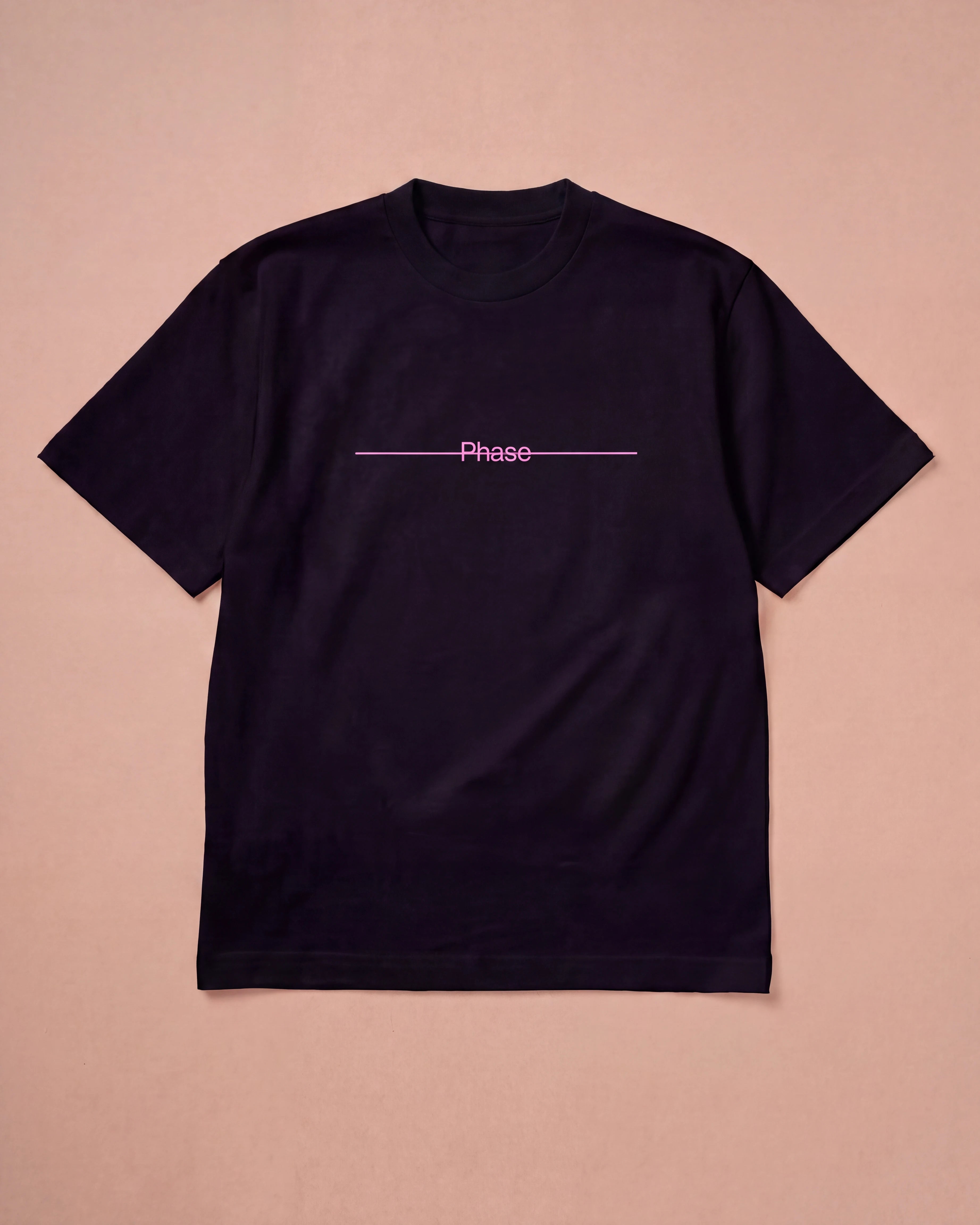 Oversized black Biweekly T-shirt with pink text 'Phase' crossed out by a long line, laying flat a beige background