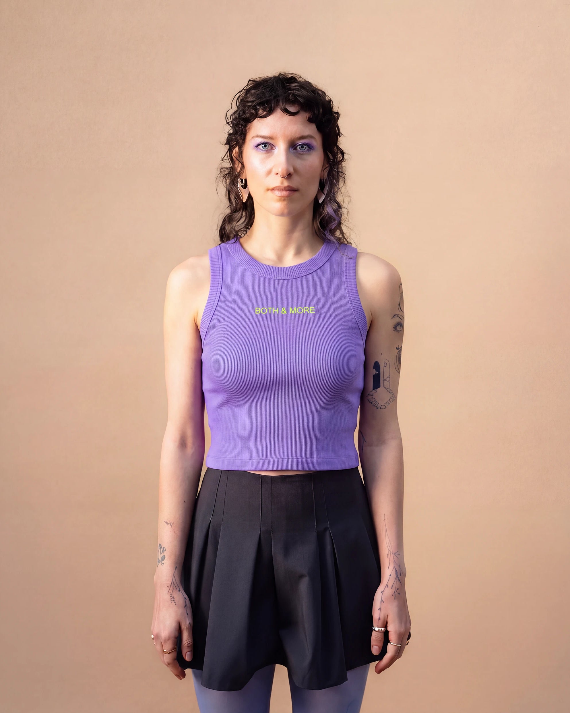 Model wearing a lilac Biweekly tank top with yellow ‘BOTH & MORE’ text, front view against a beige background