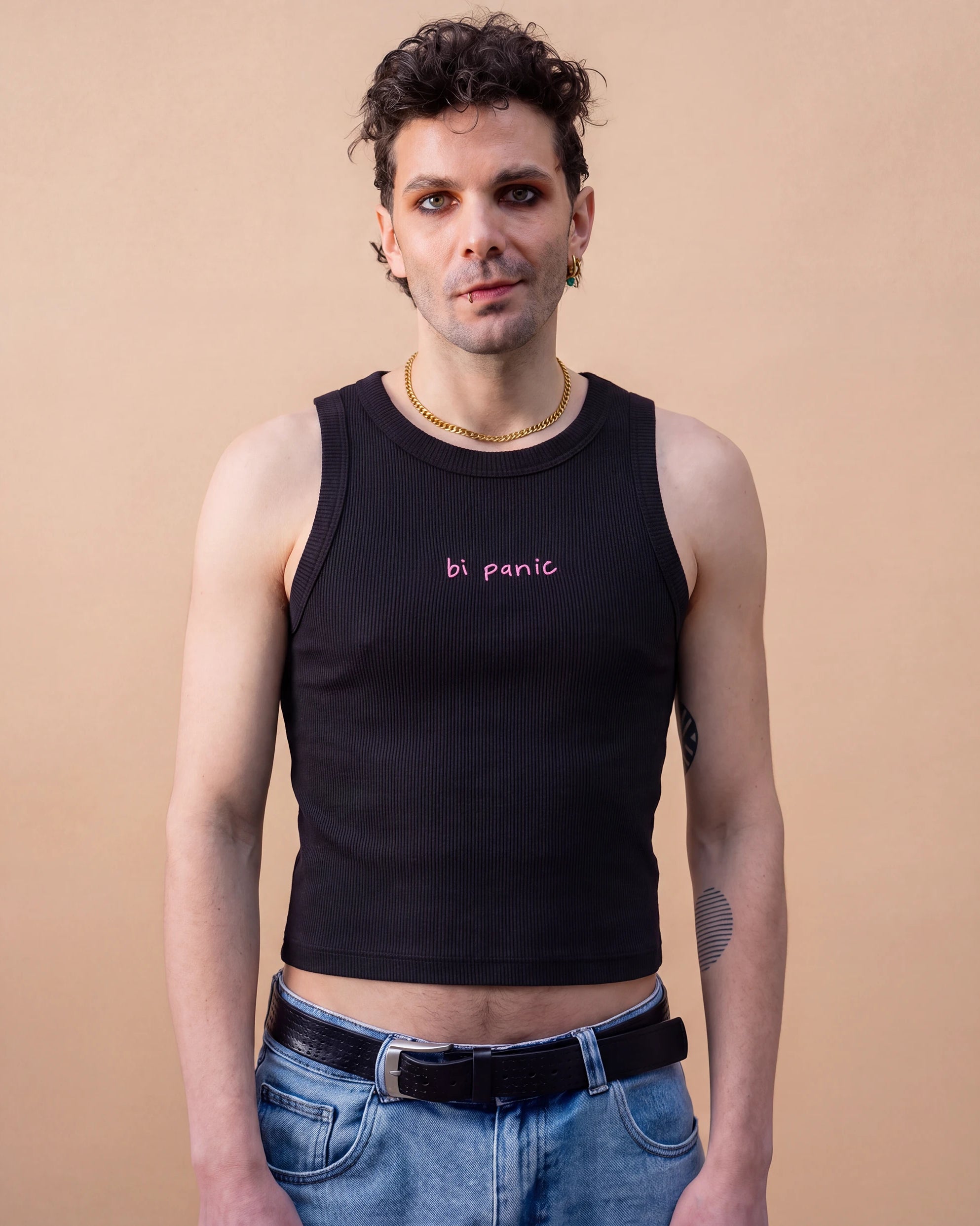 Model wearing a black Biweekly tank top with pink ‘bi panic’ text, front view against a beige background