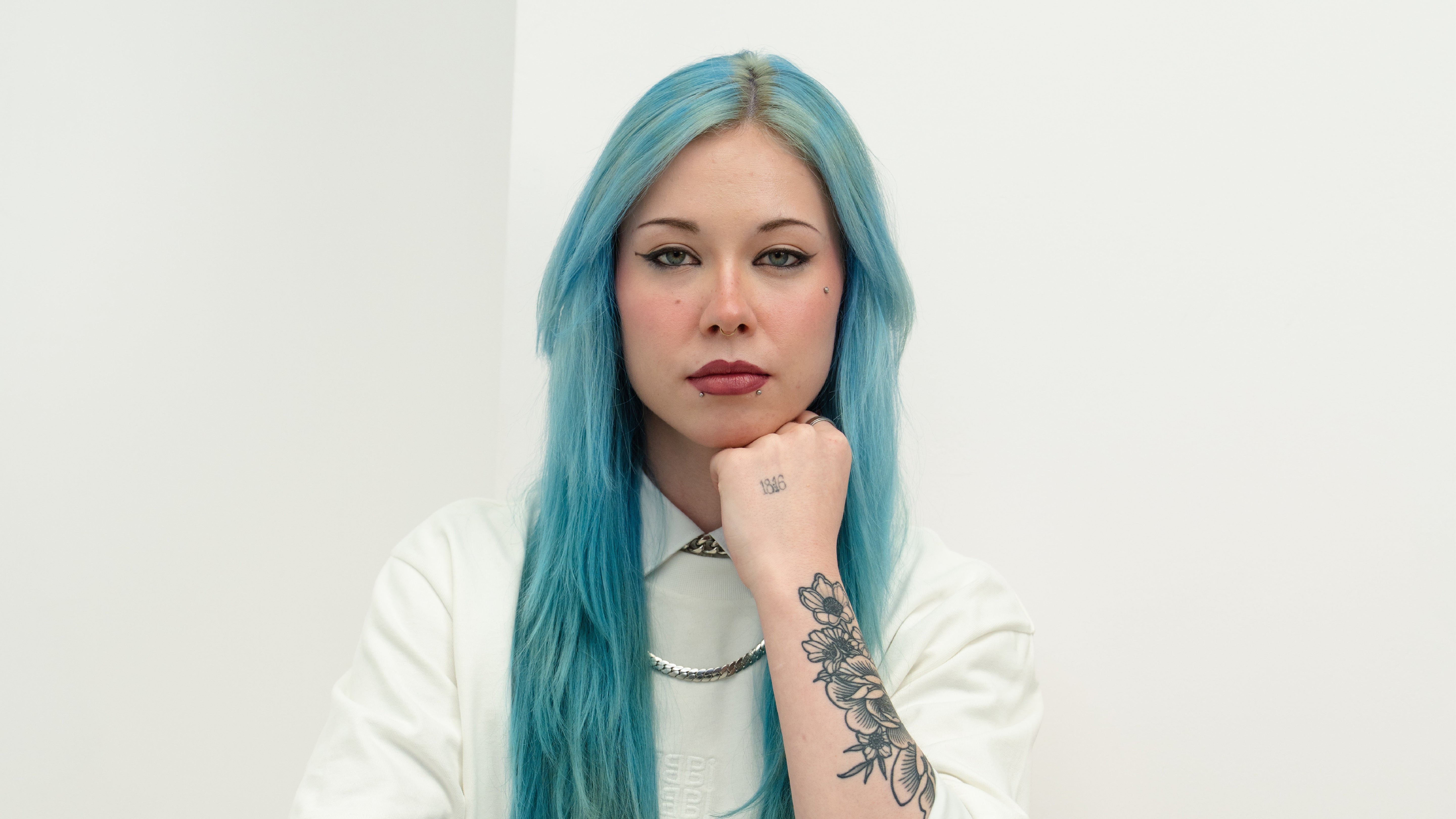 Blue haired girl supporting her chin with her hand 