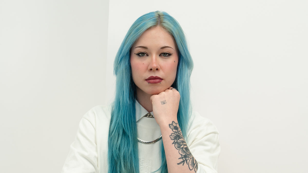 Blue haired girl supporting her chin with her hand 