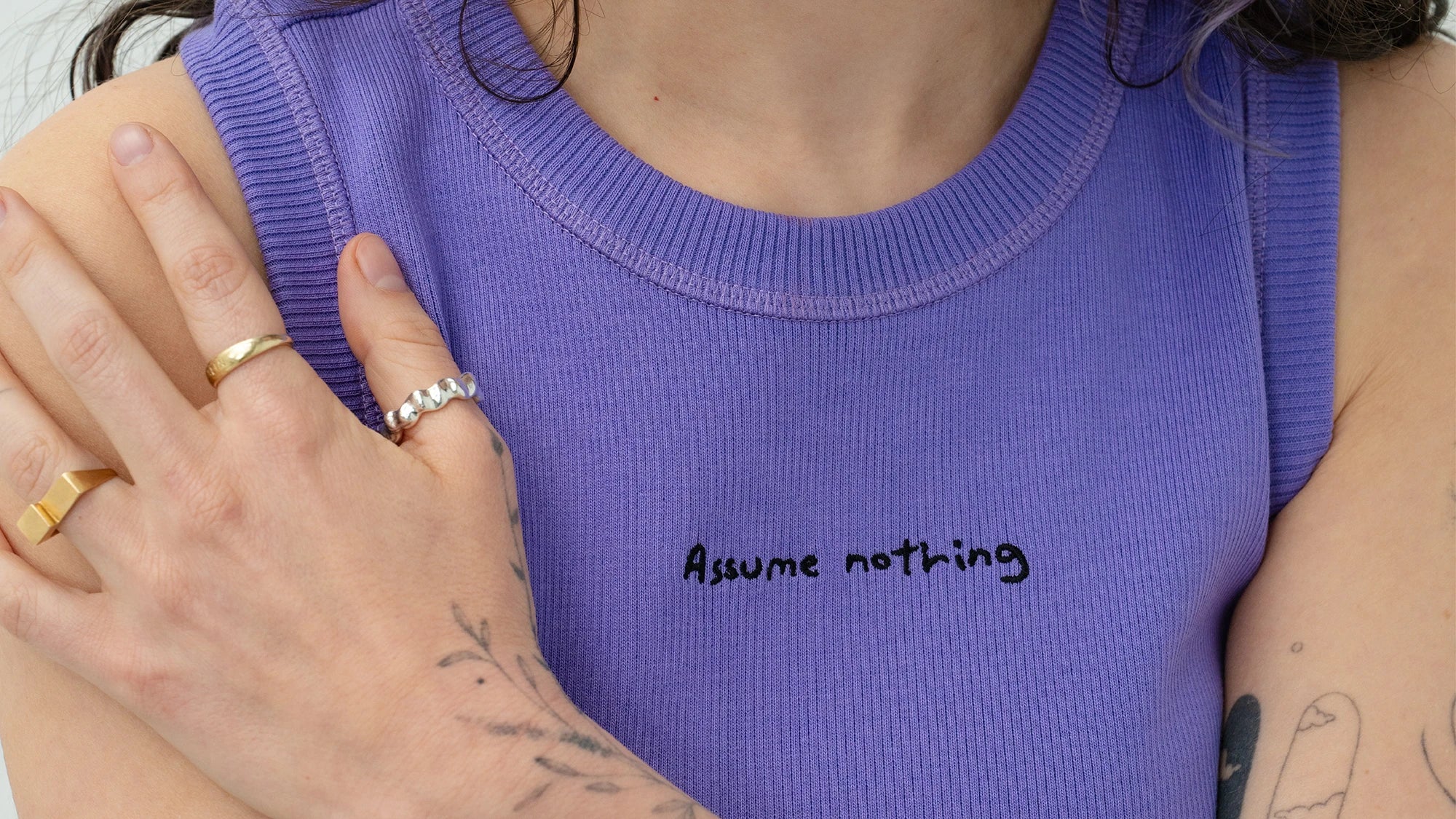 girl wearing Biweekly "assume nothing" top, close up of embroidery and hands placed on shoulder