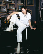 Model wearing an oversized white Biweekly T-shirt, sitting on a bar counter in a club setting