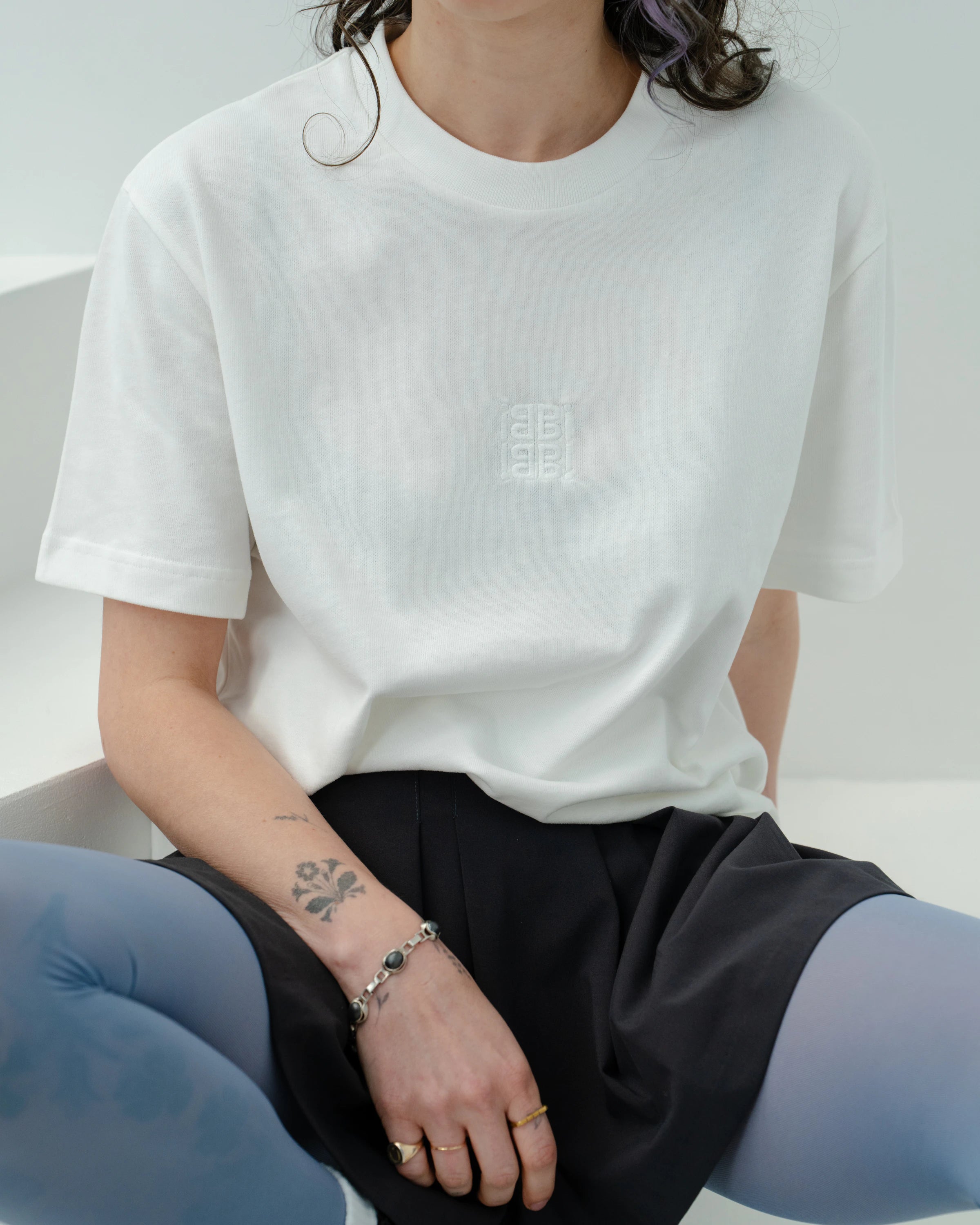 Detailshot of an oversized white Biweekly T-shirt with white ‘BiBi’ logo, front view against a white background