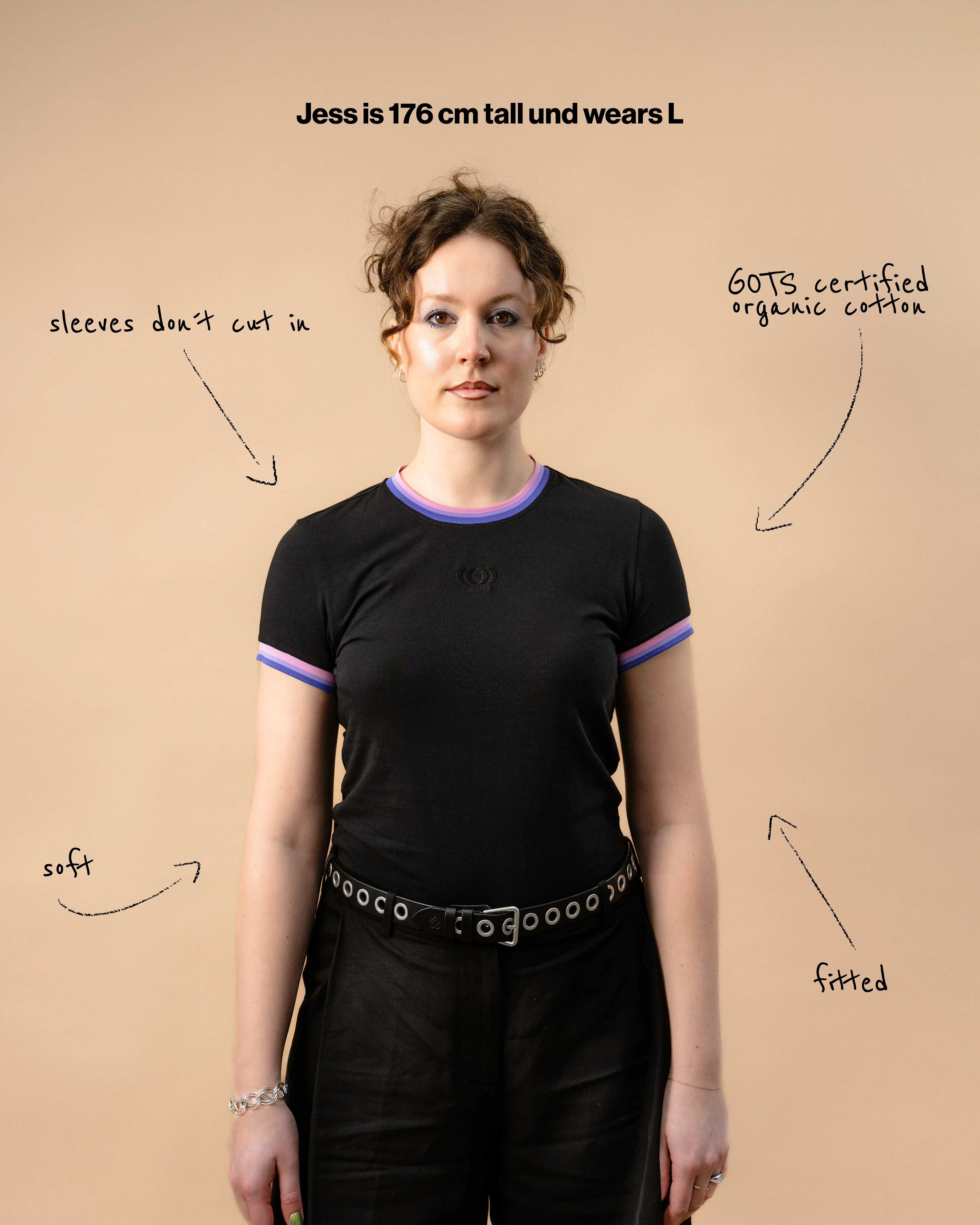 Model wearing a black Biweekly Babytee with bi pride flag trim on the collar and sleeves and black logo in the front, front view against a beige background. Text that gives information about the top. 
