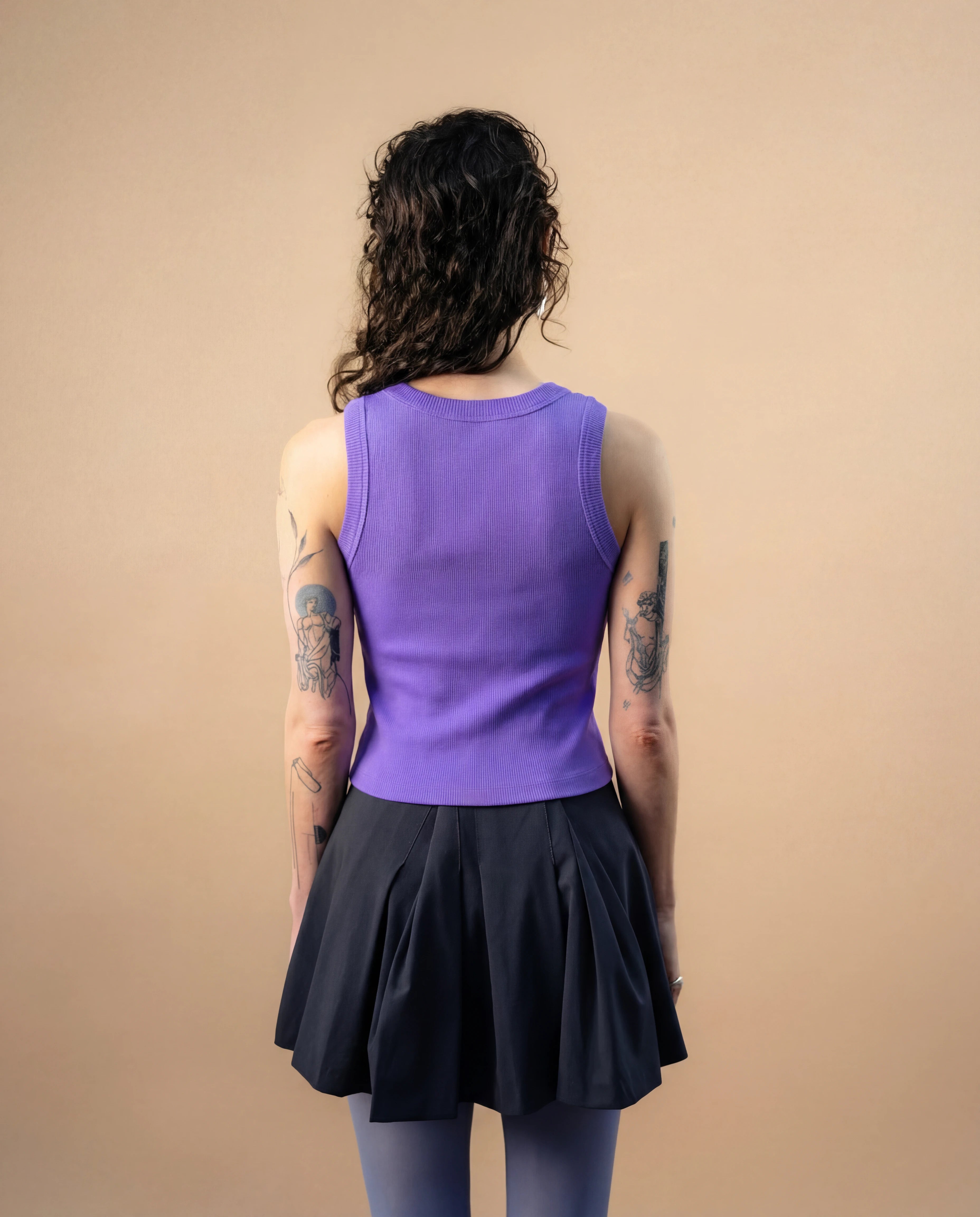 Model wearing a lilac Biweekly tank top, back view against a beige background
