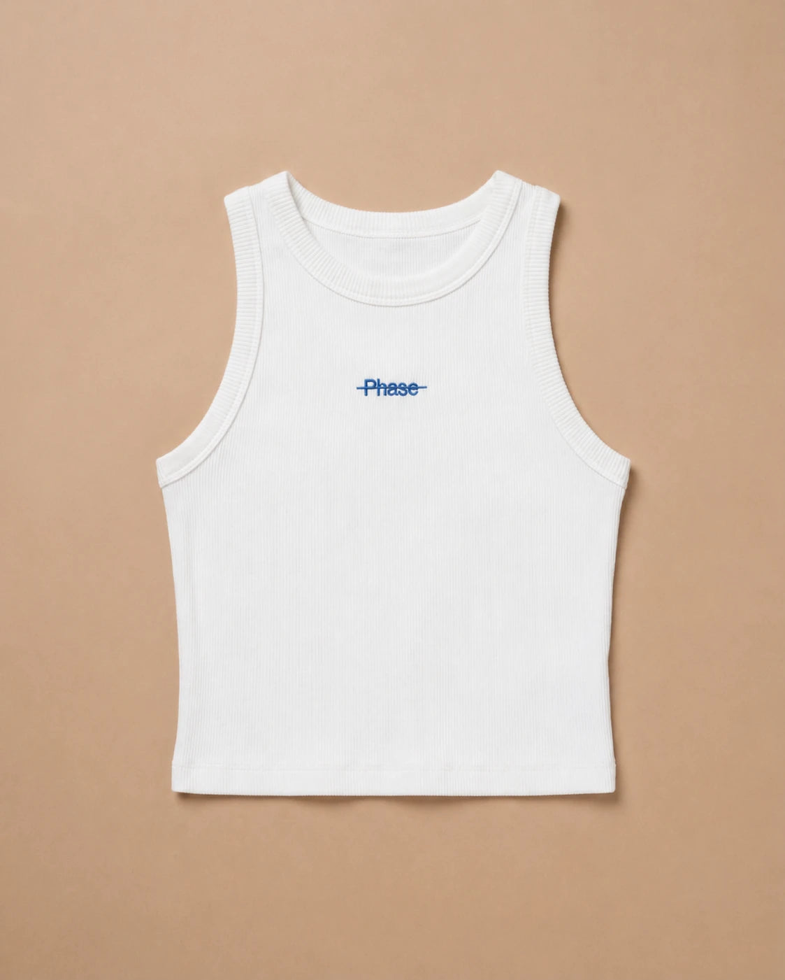 White Biweekly tank top with blue ‘Phase’ text that is crossed out, laying flat against a beige background
