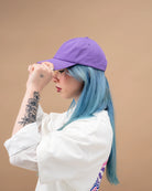 Model wearing a lilac Biweekly cap, side view against a beige background