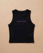 Black Biweekly tank top with lilac ‘Kiss Who You Want’ text, laying flat against a beige background
