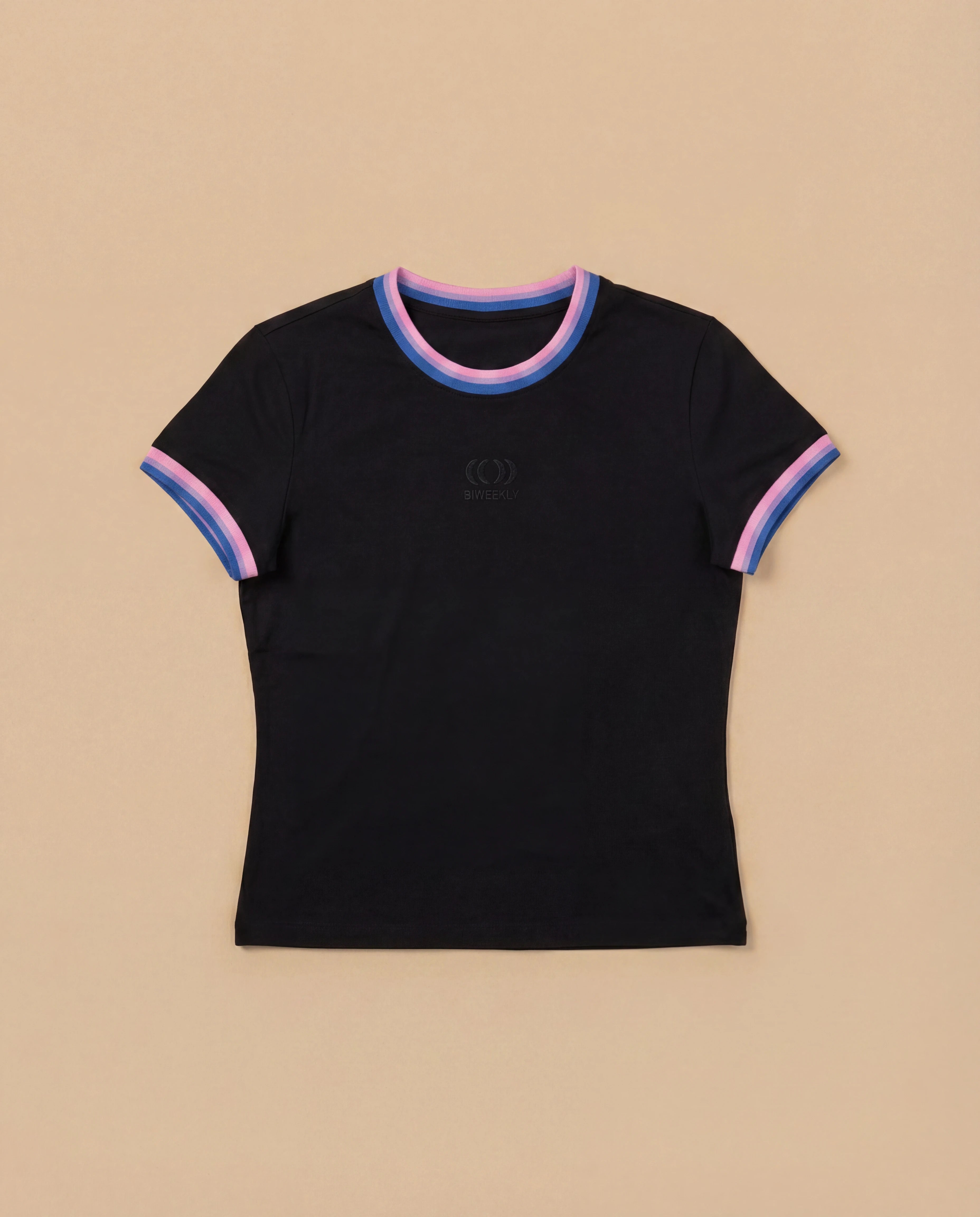 Black Biweekly babytee with bi pride flag trim on the collar and sleeves and black logo in the front, laying flat against a beige background