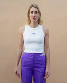 Model wearing a white Biweekly tank top with blue ‘Phase’ text that is crossed out, front view against a beige background