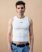 Model wearing a white Biweekly tank top with blue ‘Phase’ text that is crossed out, front view against a beige background