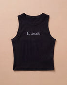 Black Biweekly tank top with white ‘Bi, actually’ text, laying flat against a beige background
