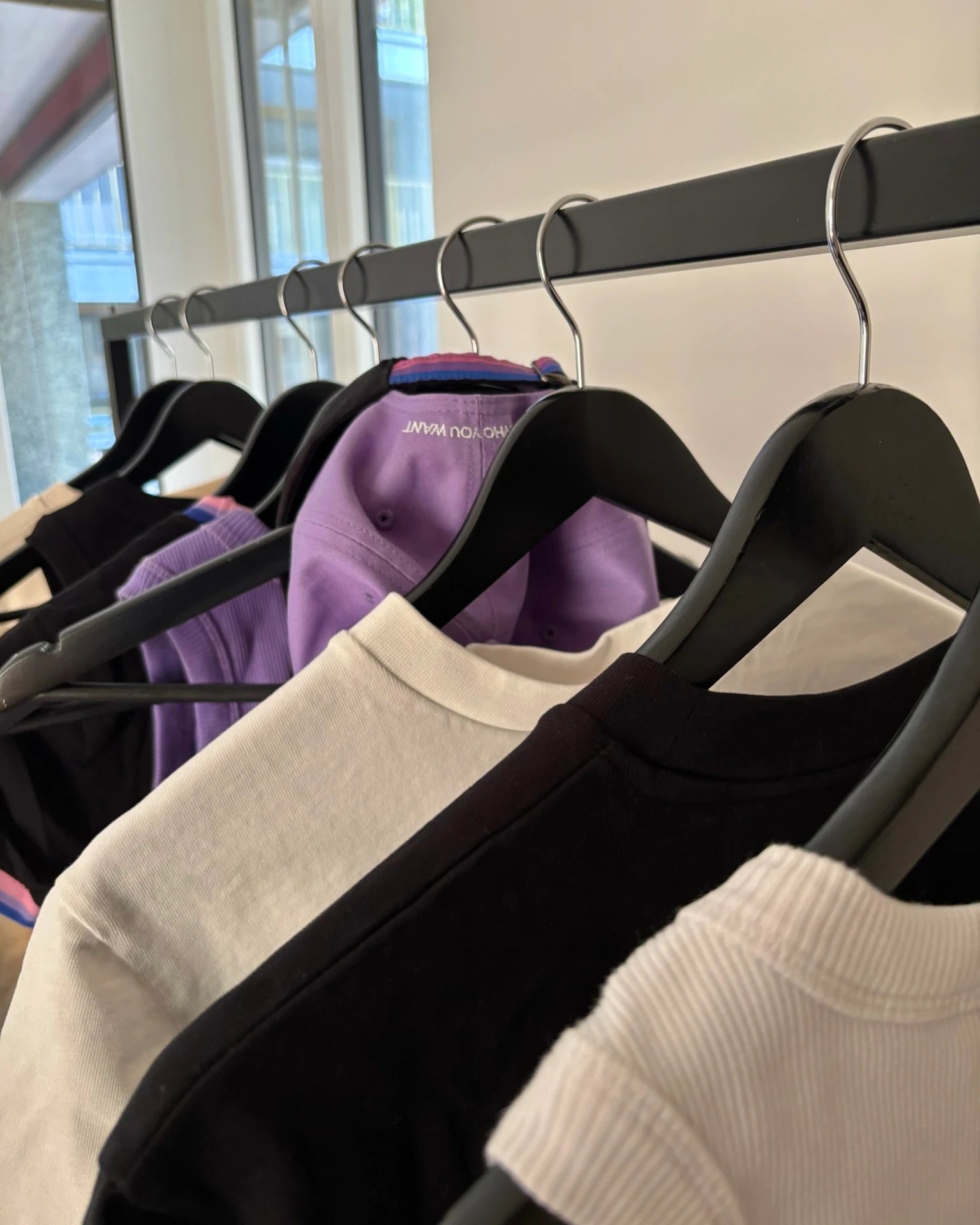Detailshot of Biweekly tops and Biweekly cap on a clothing rail