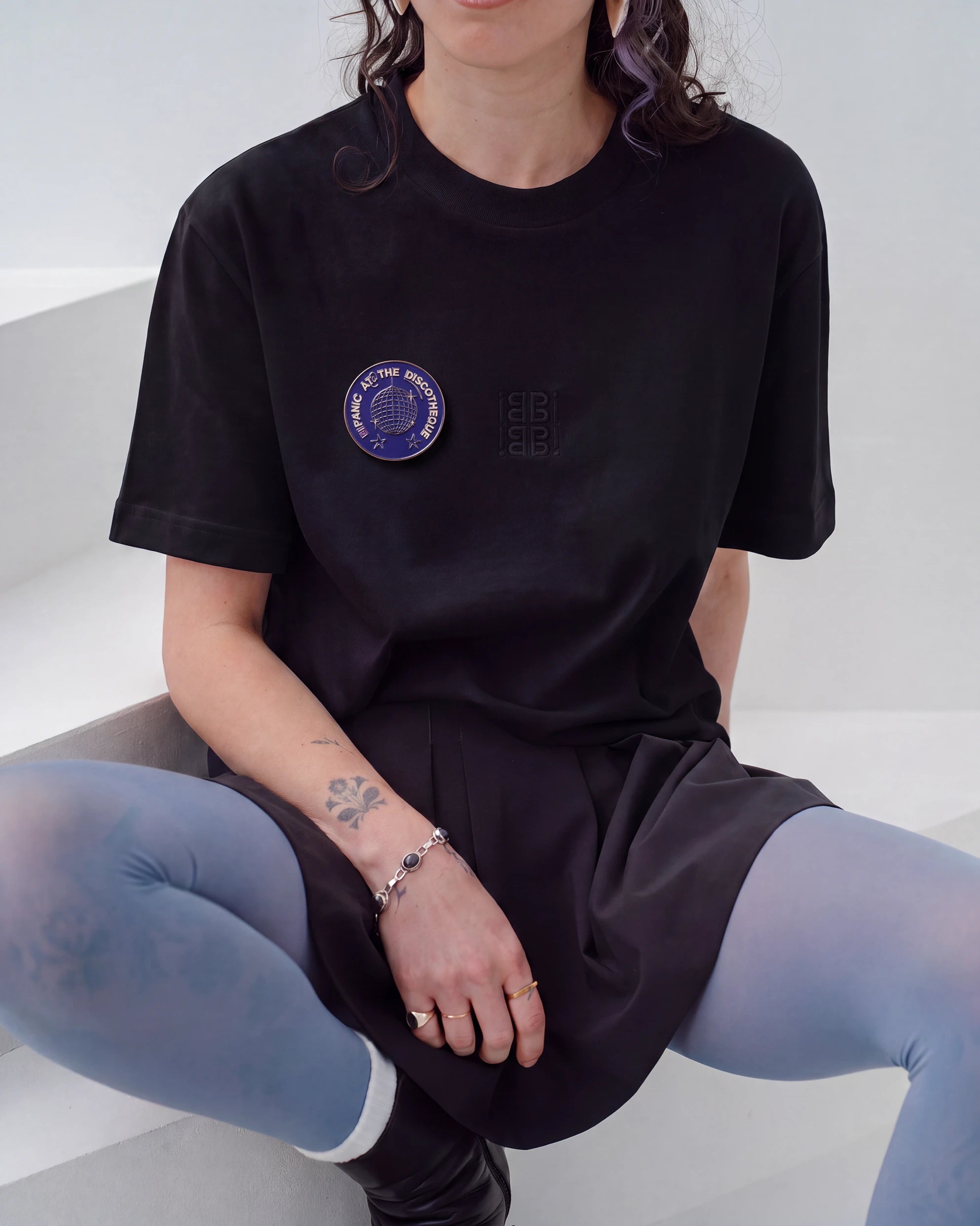 Blue Biweekly pin with 'Bipanic at the discotheque' text and disco ball illustration on a black Biweekly shirt