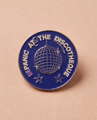 Blue Biweekly pin with 'Bipanic at the discotheque' text and disco ball illustration, flatlay against a beige background
