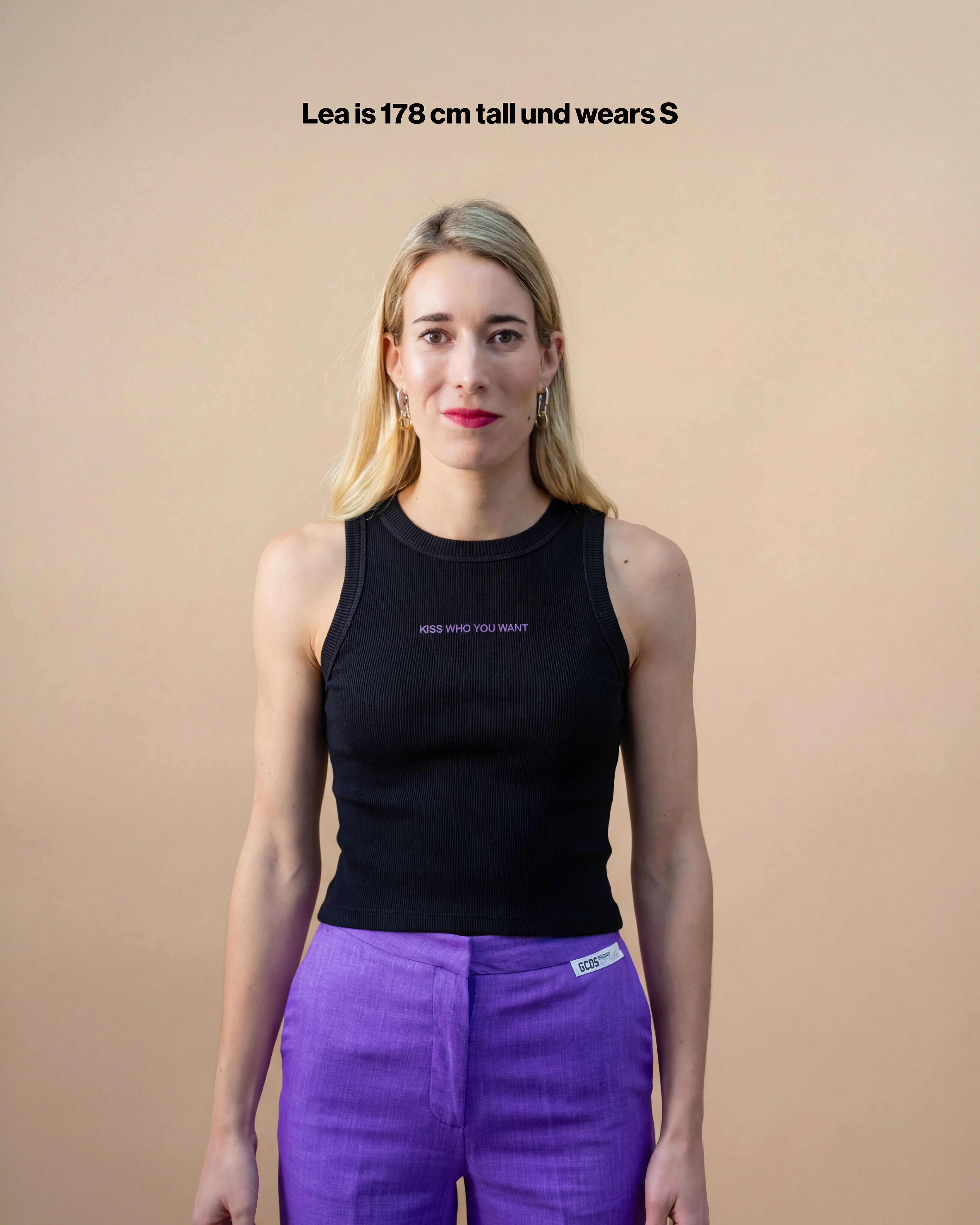 Model wearing a black Biweekly tank top with lilac "Kiss who you want" embroidery, front view against a beige background with the text "Lea is 178cm tall and wears S"