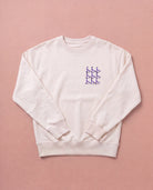Beige Biweekly crewneck with lilac playful spicy graphic print on right chest area, front view, laying flat on a beige background