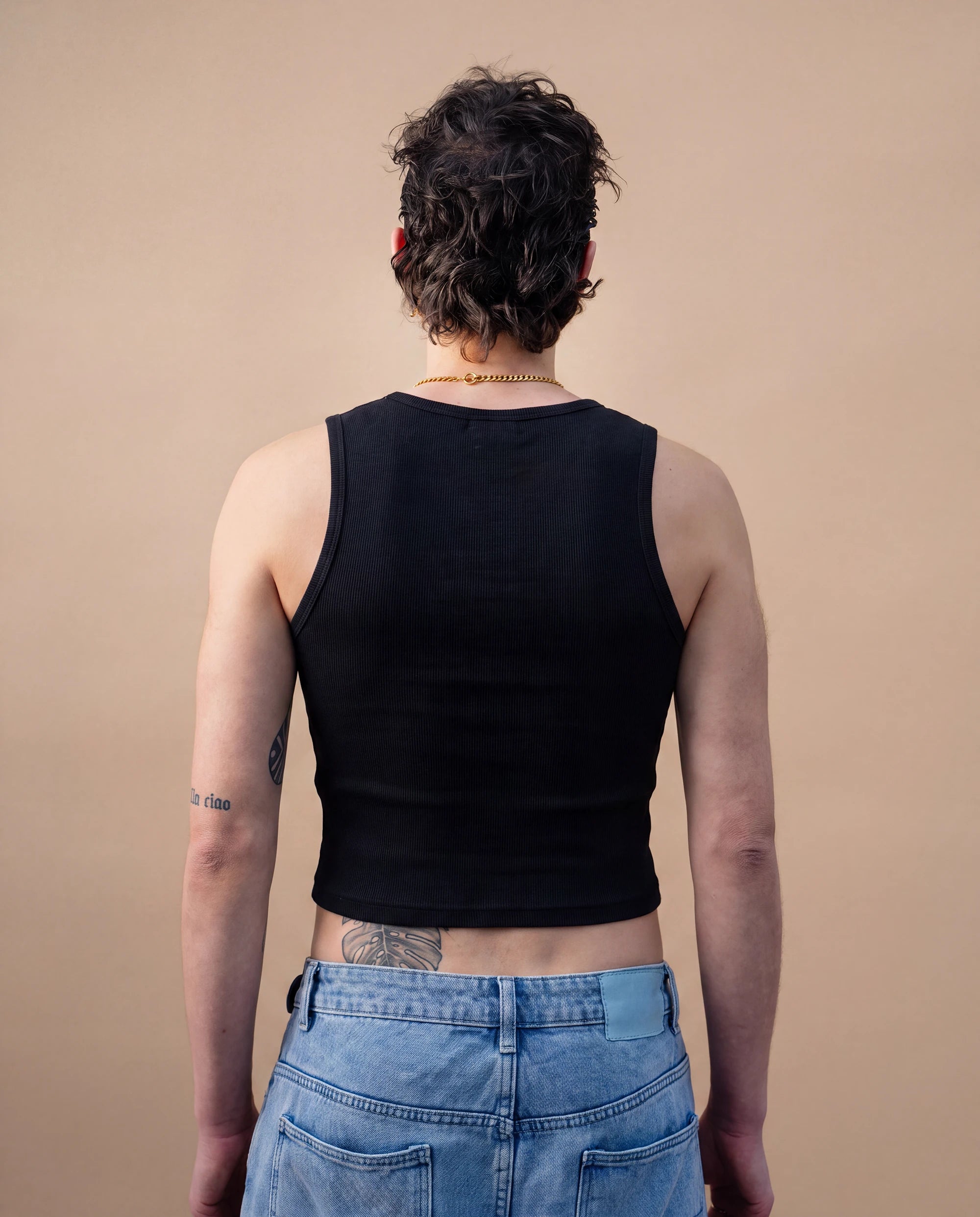 Model wearing a black Biweekly tank top, back view against a beige background