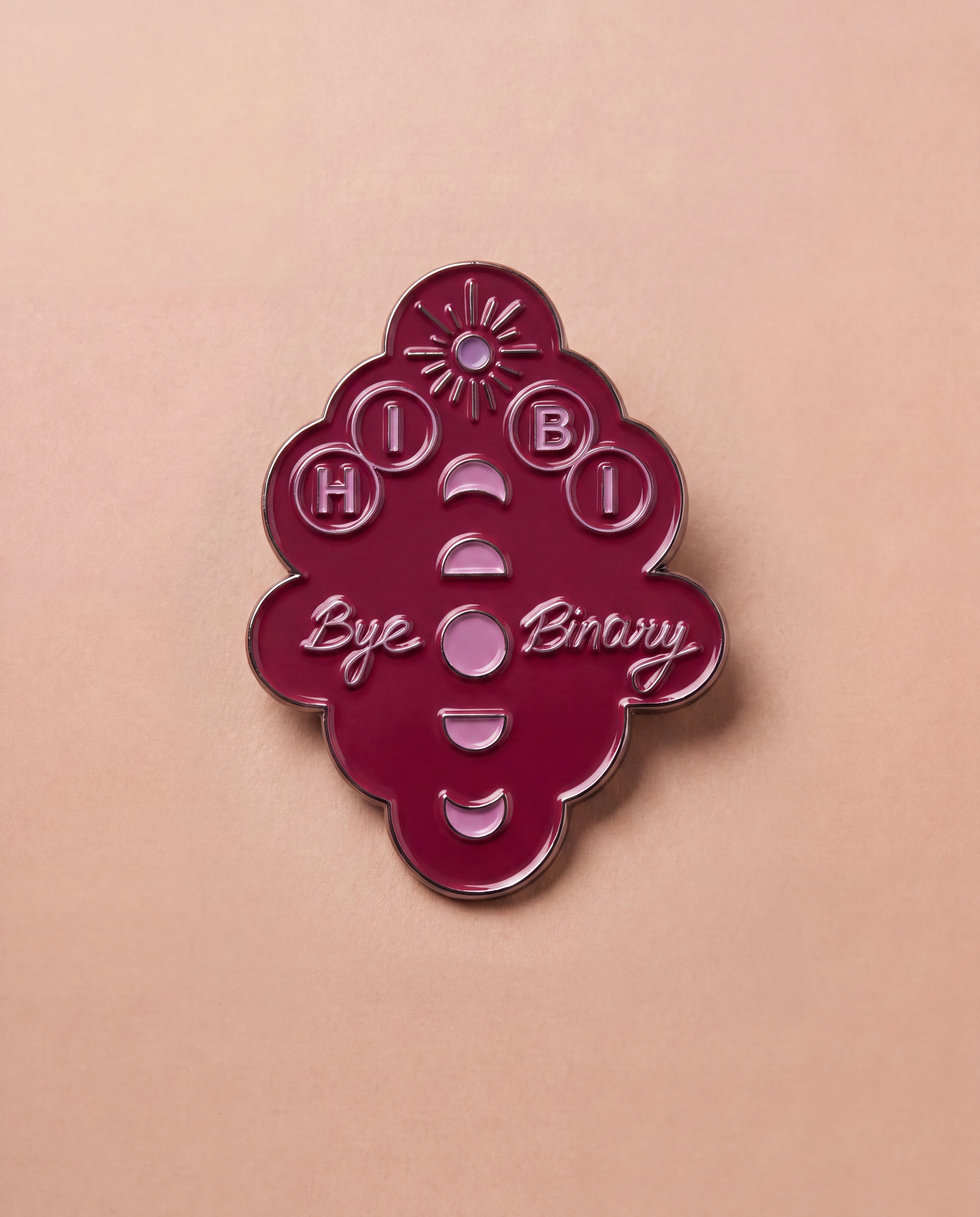 Burgundy Biweekly pin with 'Hi Bi - Bye Binary' text and moon phase illustration, flatlay against a beige background