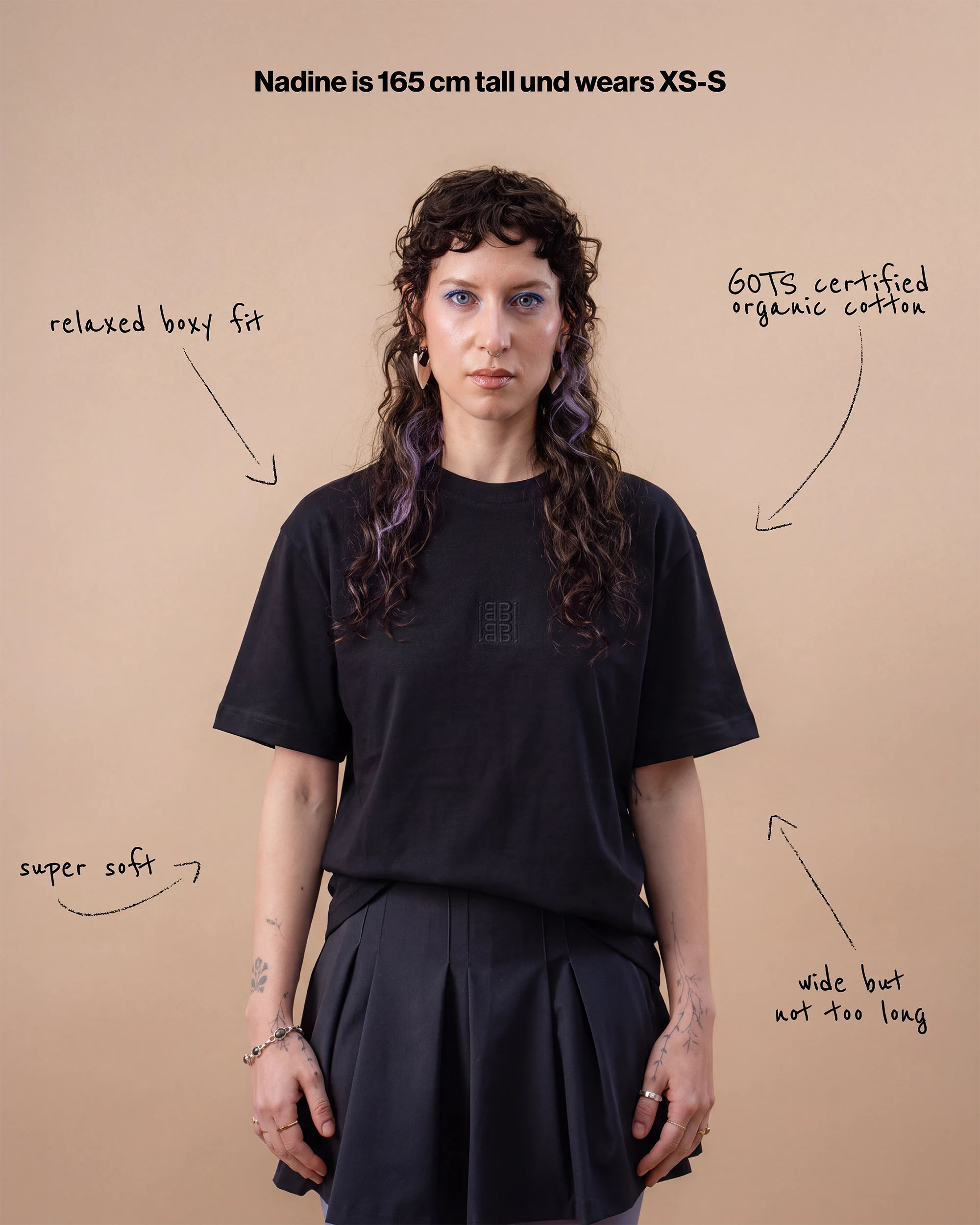 Model wears an oversized black Biweekly T-shirt with white ‘BiBi’ logo, front view against a beige background. With text that gives information on the shirt. 