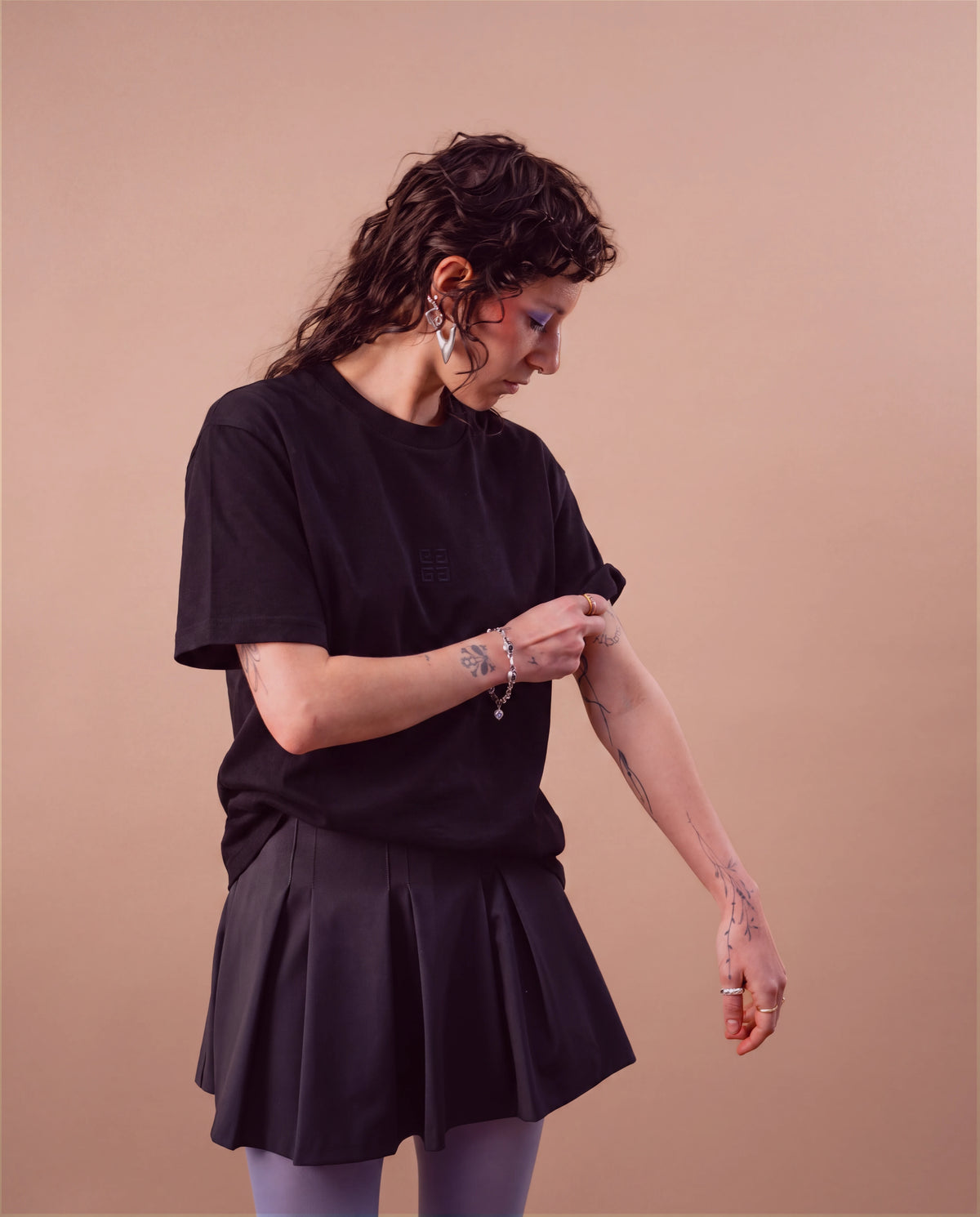 Model wears an oversized black Biweekly T-shirt with black ‘BiBi’ logo, front view against a beige background. Model is adjusting her sleeve.