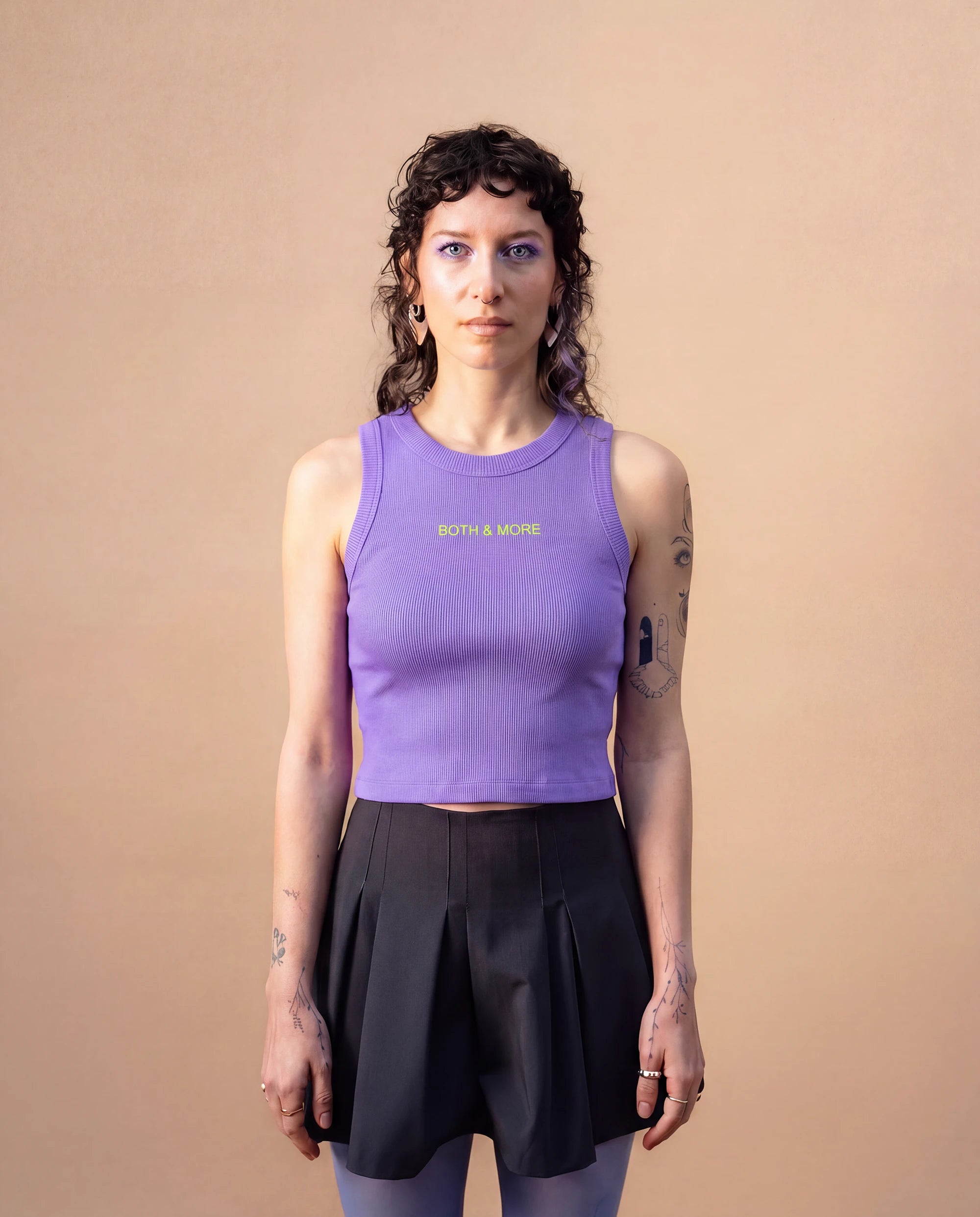 Model wearing a lilac Biweekly tank top with yellow ‘BOTH & MORE’ text, front view against a beige background