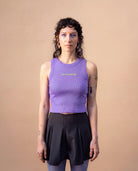 Model wearing a lilac Biweekly tank top with yellow ‘BOTH & MORE’ text, front view against a beige background