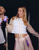 Model wears Biweekly keychain in bi pride flag colors with silver carabiner and blue yarn on skirt loops while dancing in a club scenario