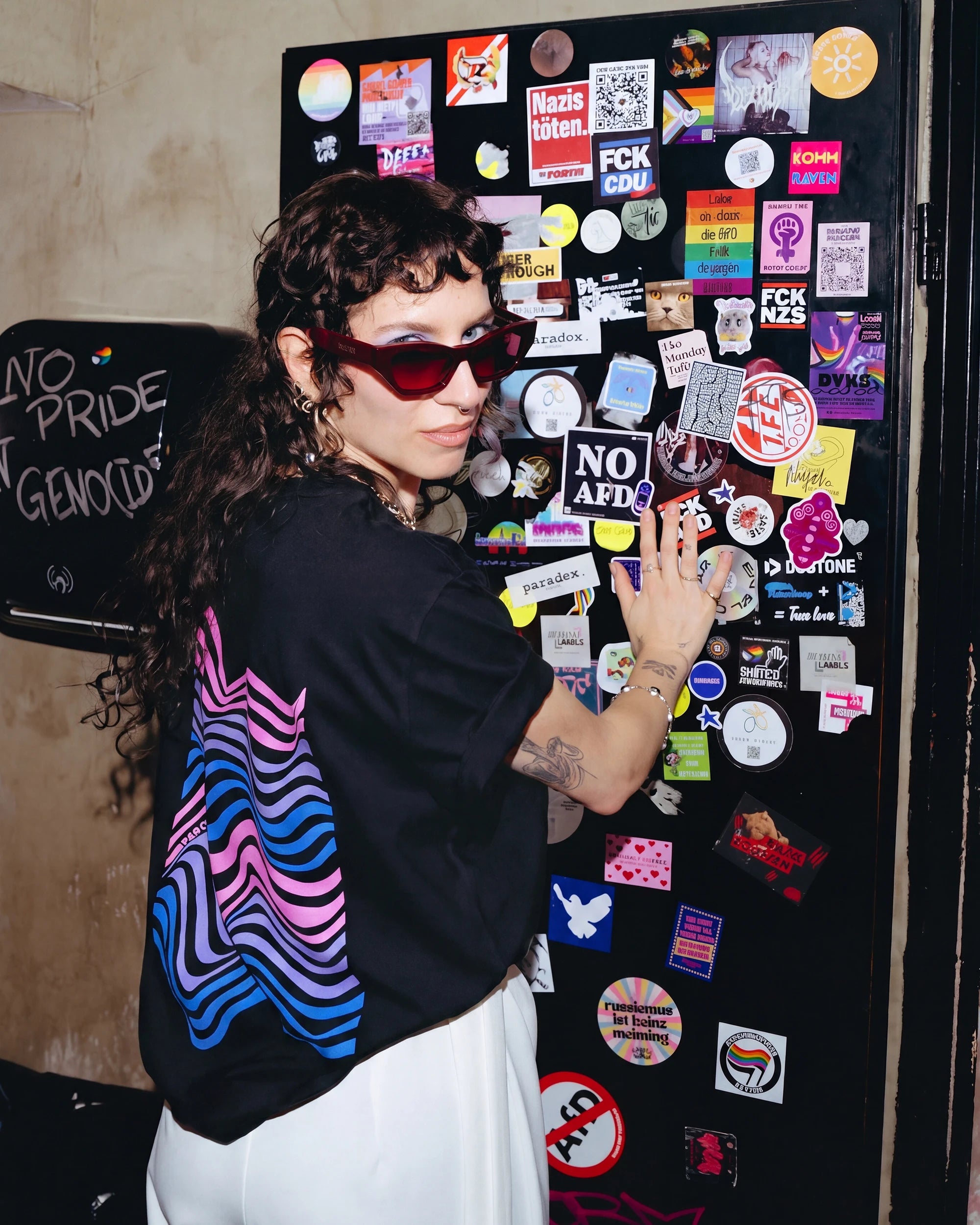 Model wearing an oversized black Biweekly T-shirt with a bi coloured wave print in a club setting