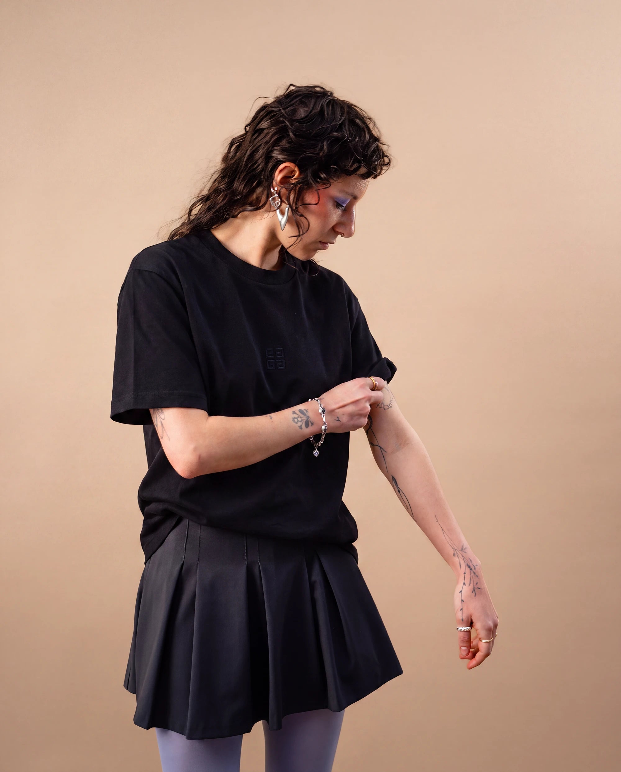 Model wears an oversized black Biweekly T-shirt with black ‘BiBi’ logo, front view against a beige background. Model is adjusting her sleeve.
