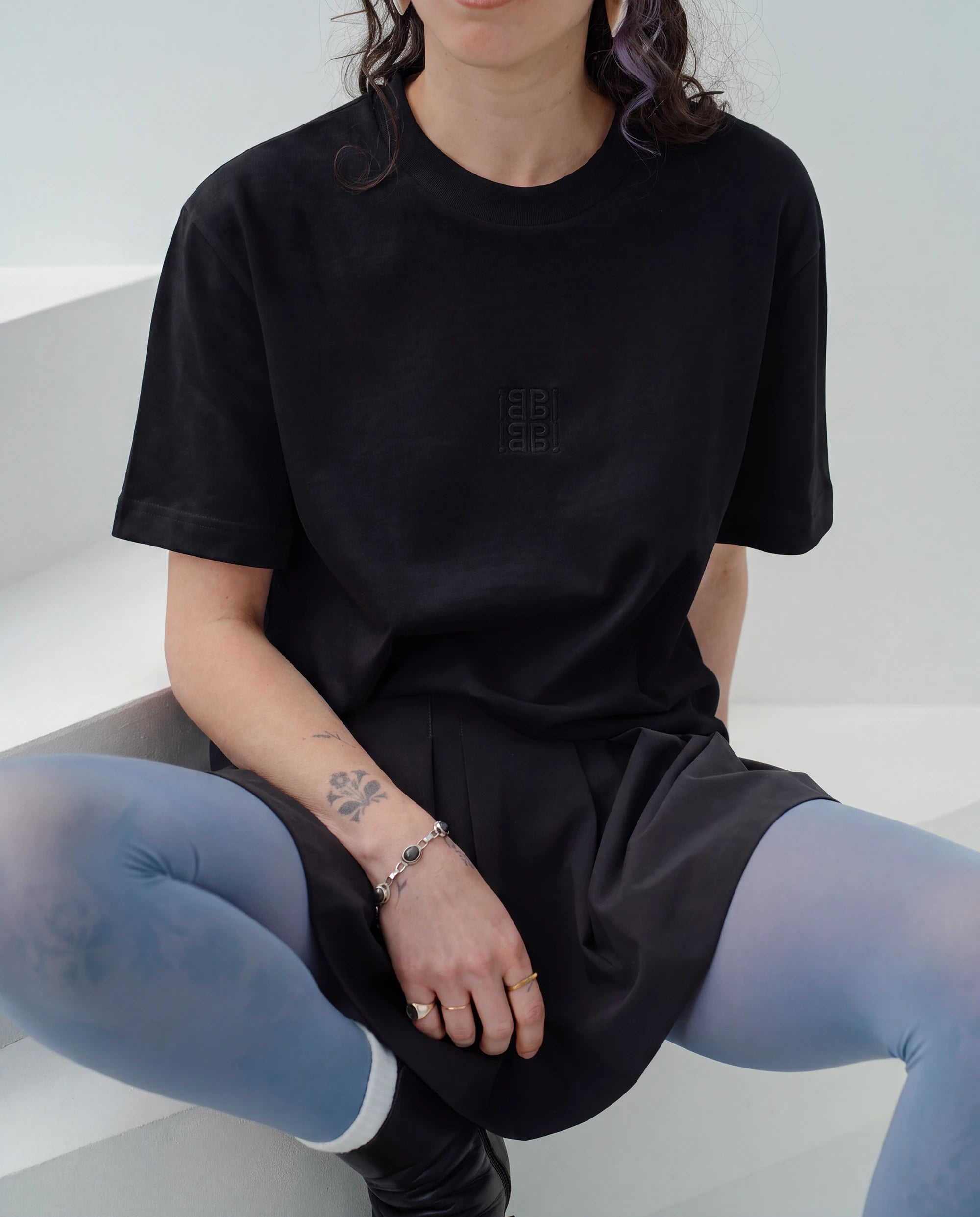 Detailshot of an oversized white Biweekly T-shirt with white ‘BiBi’ logo, front view against a white background