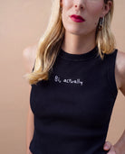 Detail view of a black Biweekly tank top with white ‘Bi, actually’ text against beige background