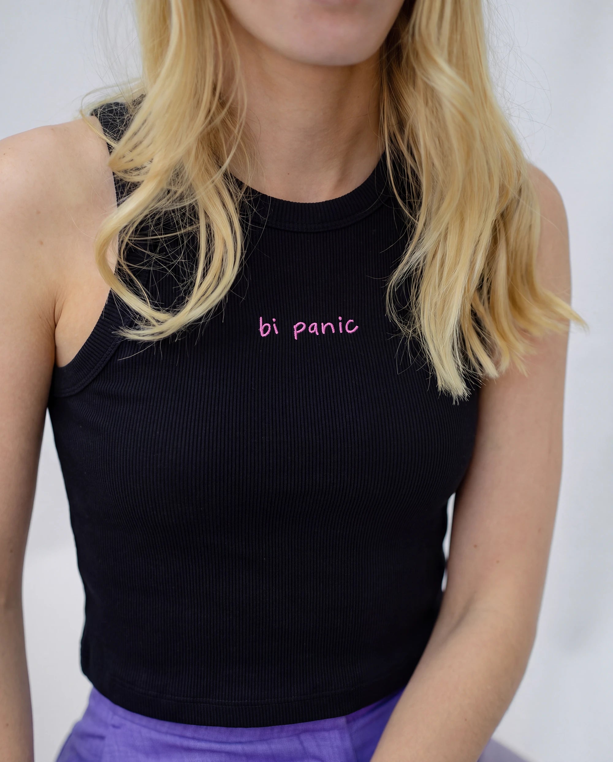 Detail view of a black Biweekly tank top with pink ‘bi panic’ text against white background