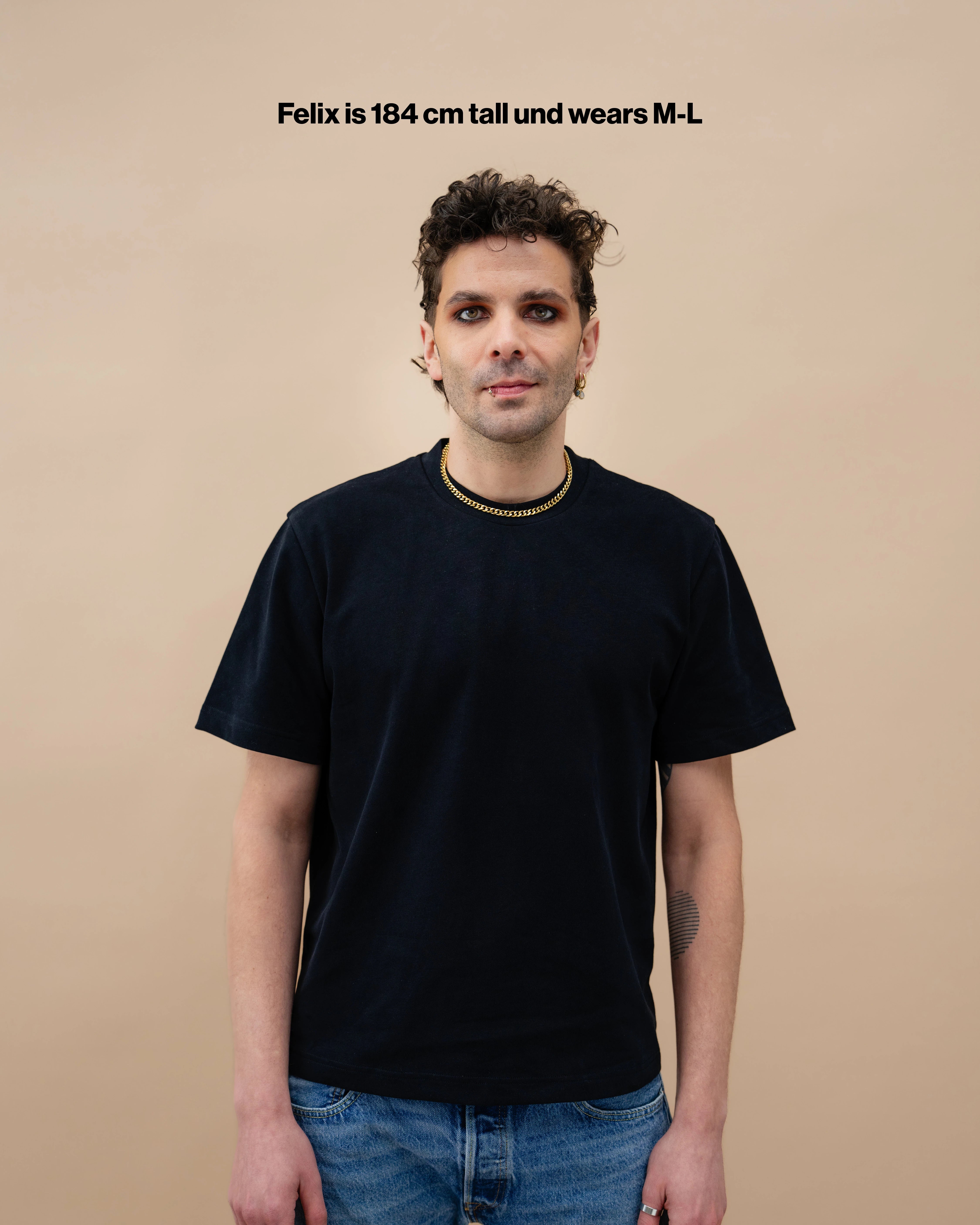 Model wearing a black Biweekly oversized tee, front view against a beige background with the text "Felix is 184cm tall and wears M-L"