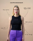 Model wearing a black Biweekly tank top with lilac ‘Kiss Who You Want’ text, front view against a beige background. Text that gives information about top. 